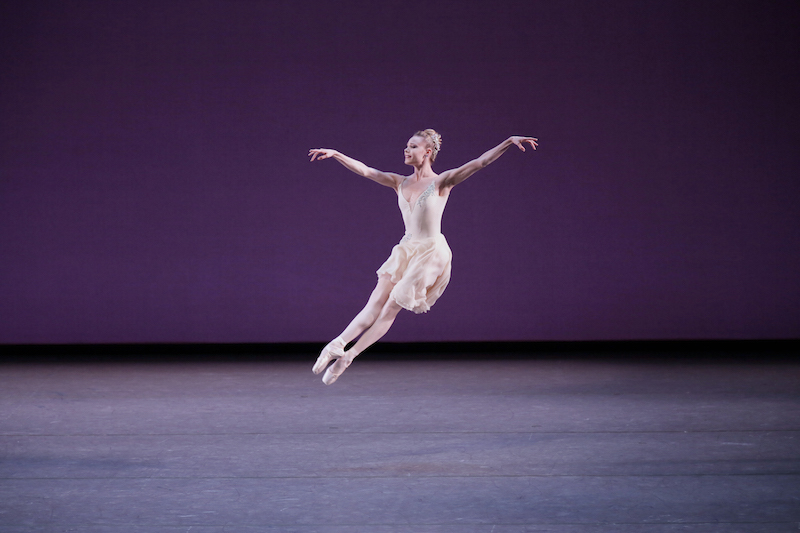 Sara Mearns is airborn, both of her legs beat together creating a scissor motion